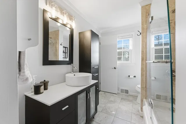 a bathroom with a shower sink vanity mirror and toilet