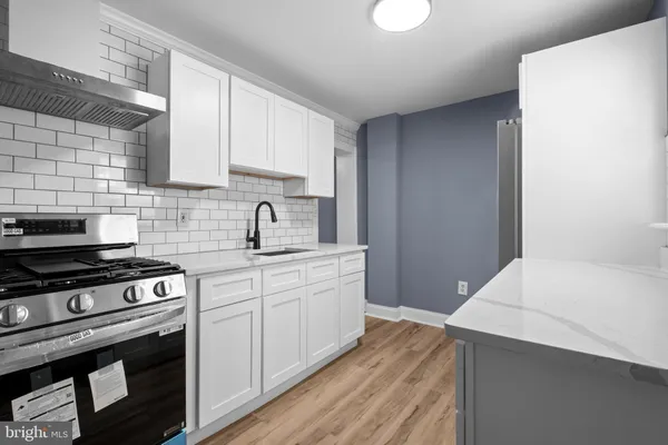 a kitchen with stainless steel appliances a stove a sink and white cabinets