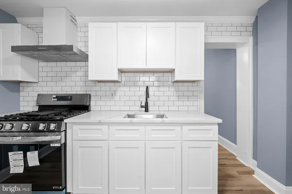a kitchen with white cabinets sink and stove