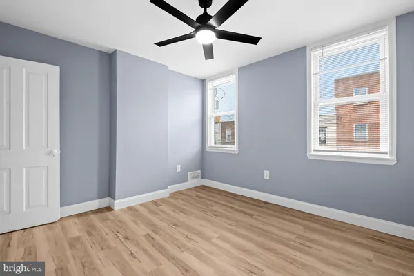 a view of empty room with wooden floor and fan