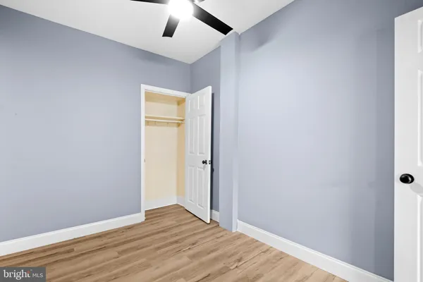 an empty room with wooden floor cabinet and ceiling fan