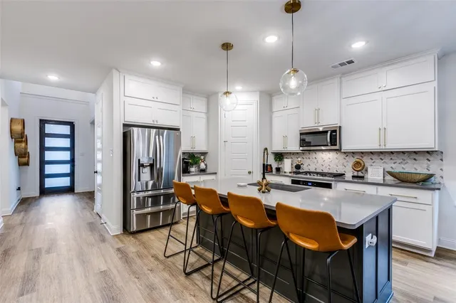 a large kitchen with stainless steel appliances granite countertop a stove a refrigerator a kitchen island a table and chairs