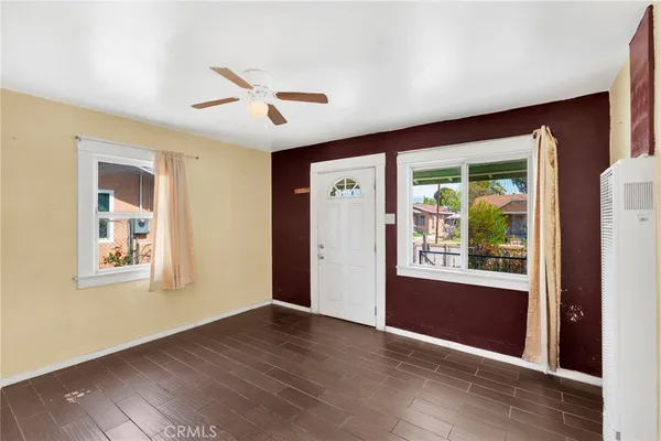 a view of an empty room with wooden floor and a window