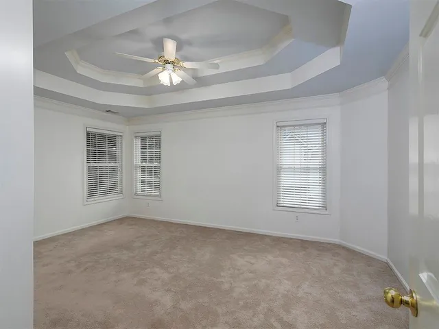 an empty room with a chandelier fan and windows