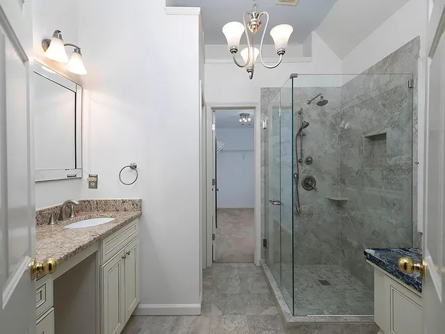 a bathroom with a granite countertop sink a toilet and shower