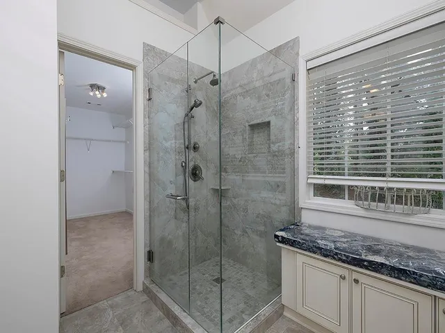 a bathroom with a granite countertop shower a mirror and a sink