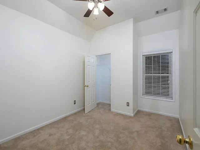 an empty room with a ceiling fan and window