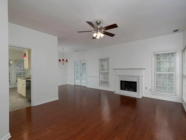 a view of empty room with wooden floor and fan