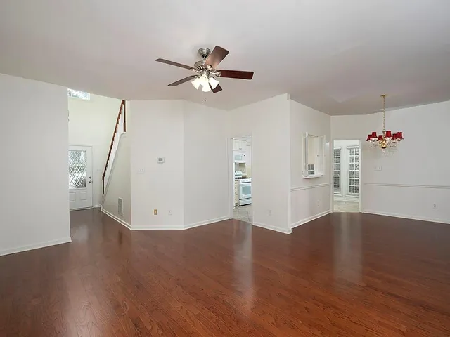 a view of empty room with wooden floor and ceiling fan