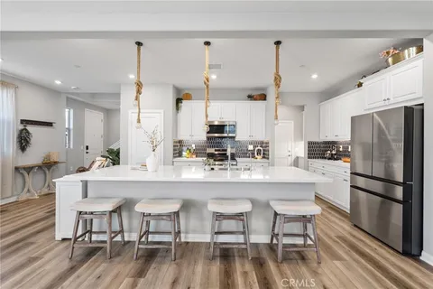 a kitchen with stainless steel appliances a dining table chairs refrigerator and microwave