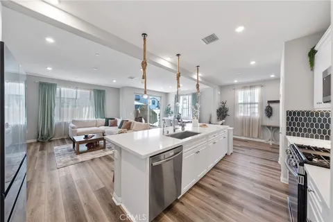 a large kitchen with kitchen island a sink dishwasher a dining table and chairs with wooden floor