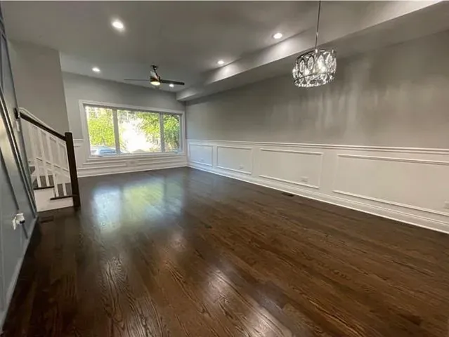an empty room with wooden floor chandelier and windows