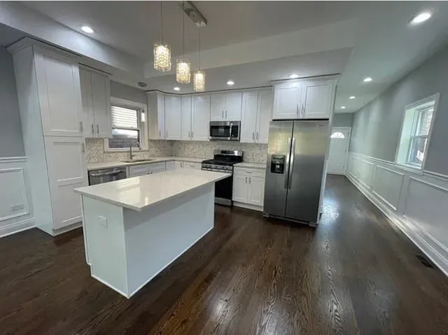 a kitchen with stainless steel appliances granite countertop a refrigerator a sink a stove and wooden floor