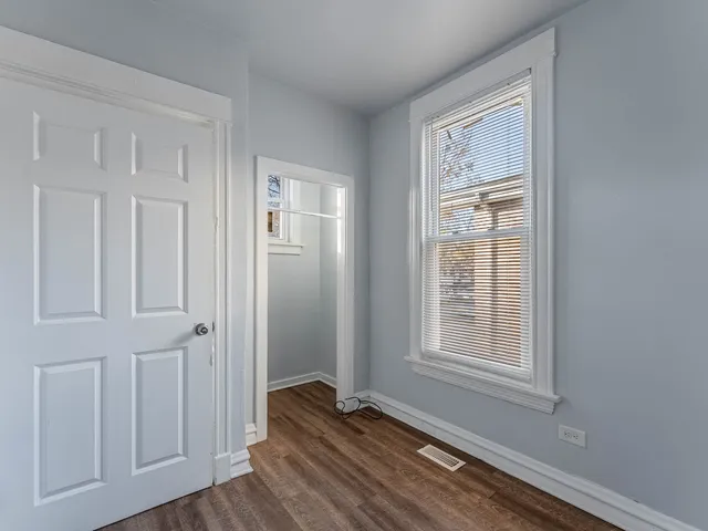 an empty room with wooden floor closet and windows