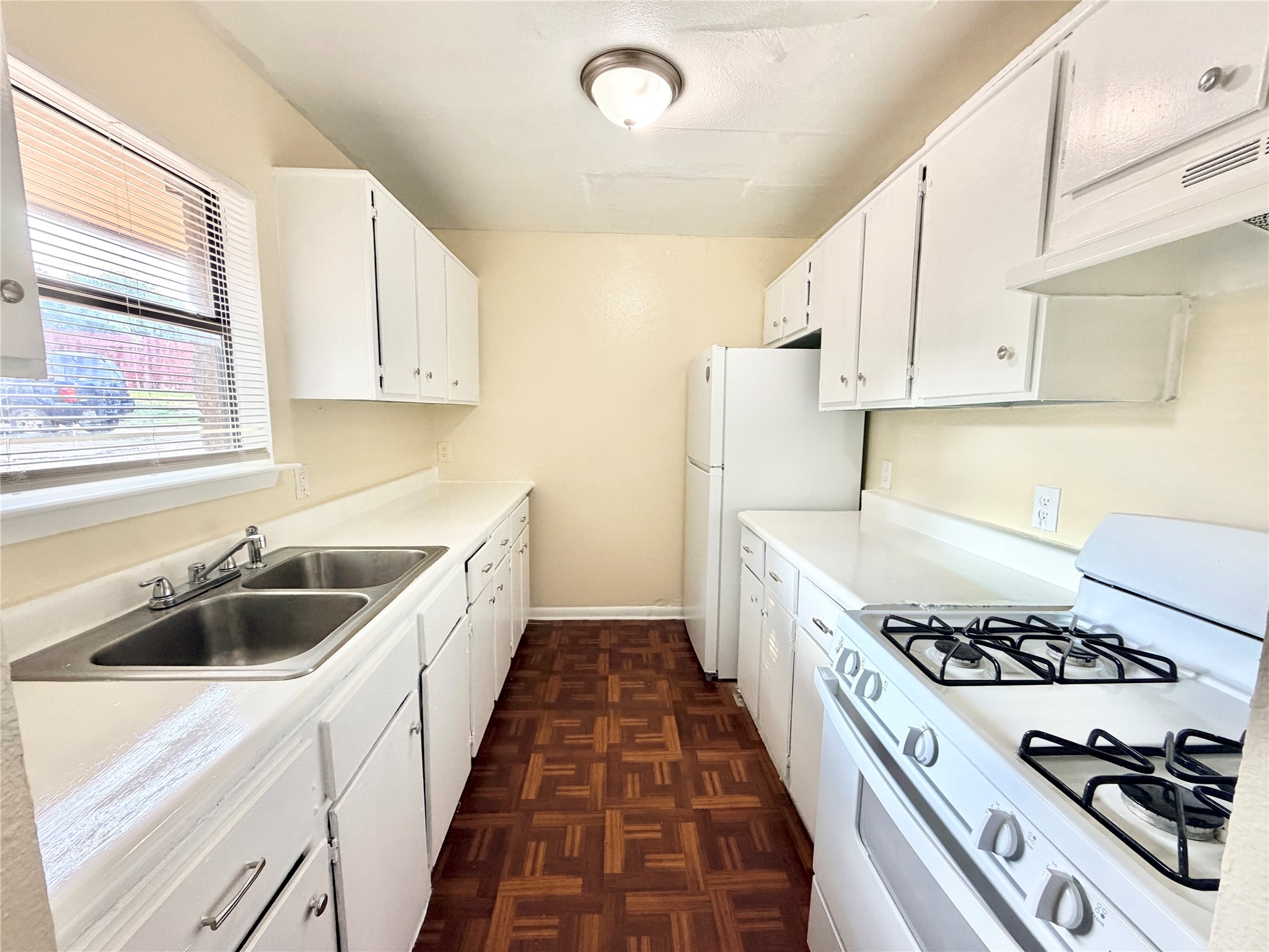 6257 Manor Road, Unit B Austin, TX 78723 - Photo 7 of 38 Galley kitchen with white cabinetry, a double basin sink, a gas range, a white refrigerator, and wood-finish flooring