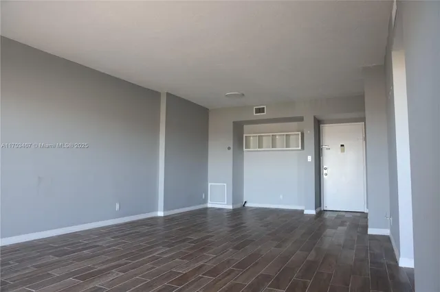 a view of an empty room with wooden floor and closet