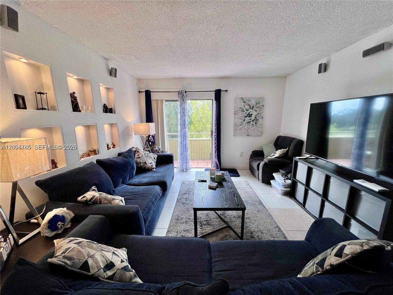 17530 Northwest 68th Avenue, Unit C4008 Hialeah, FL 33015 - Photo 18 of 26 a living room with furniture and a flat screen tv