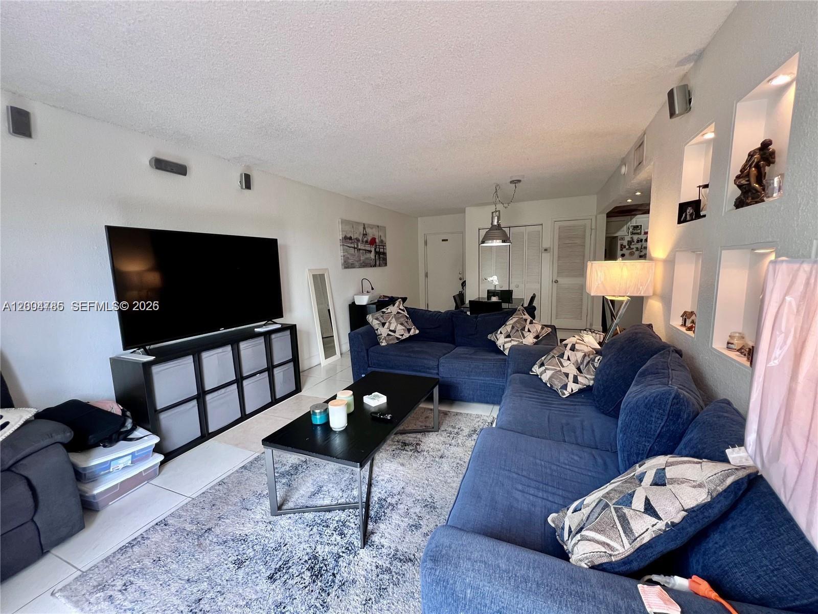 17530 Northwest 68th Avenue, Unit C4008 Hialeah, FL 33015 - Photo 19 of 26 a living room with furniture and a flat screen tv
