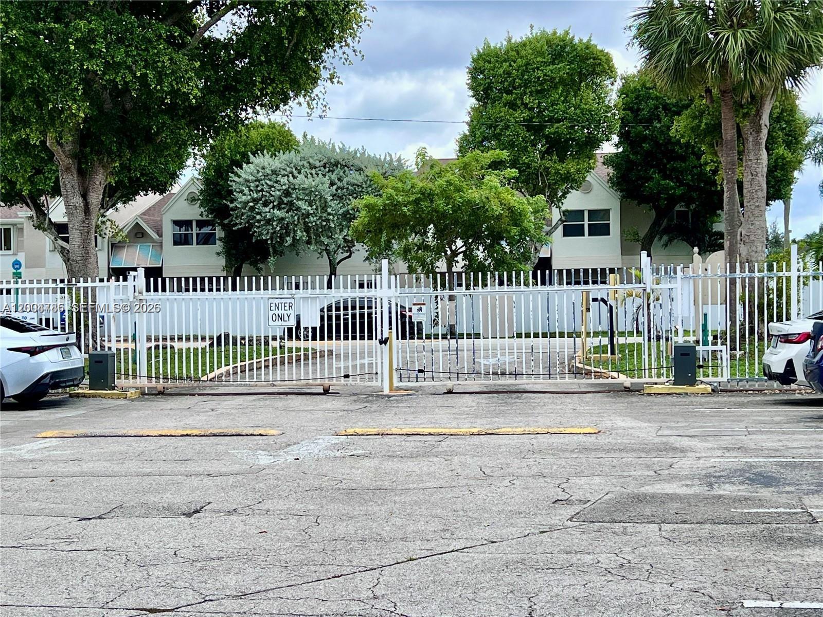 17530 Northwest 68th Avenue, Unit C4008 Hialeah, FL 33015 - Photo 25 of 26 a garden area with wooden fence and trees