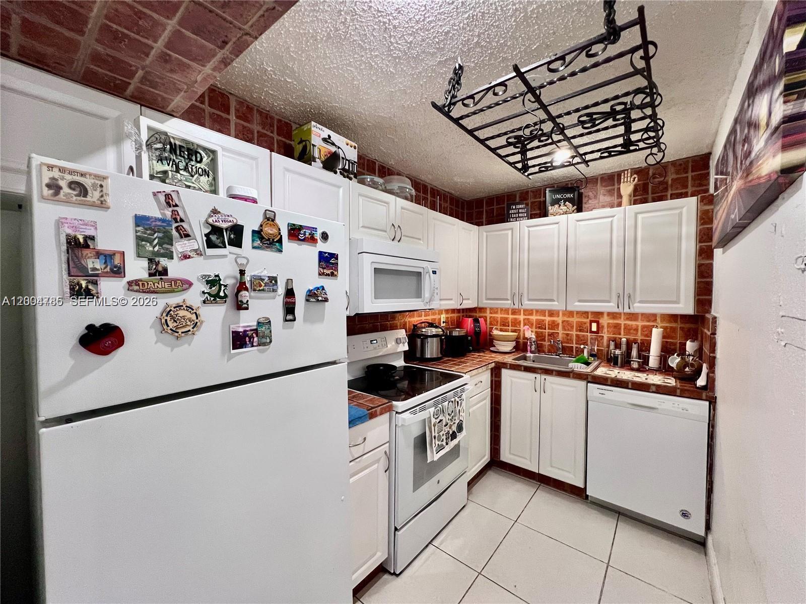 17530 Northwest 68th Avenue, Unit C4008 Hialeah, FL 33015 - Photo 7 of 26 a kitchen with lot of cabinets and white appliances
