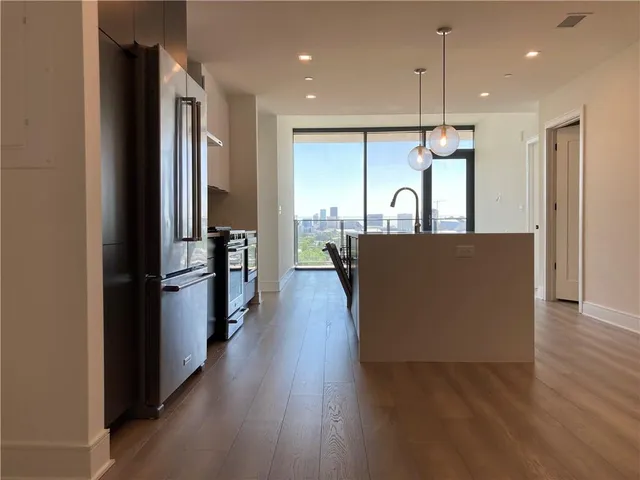 a open kitchen with stainless steel appliances granite countertop a refrigerator a oven and a wooden floor