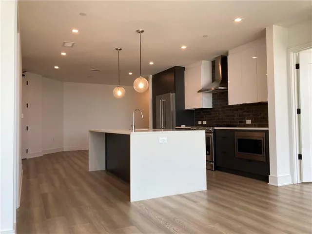 a kitchen with stainless steel appliances granite countertop a stove a refrigerator a sink and a oven with wooden floor