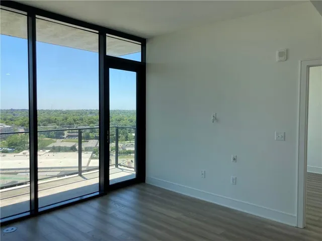 an empty room with wooden floor and windows with sliding door