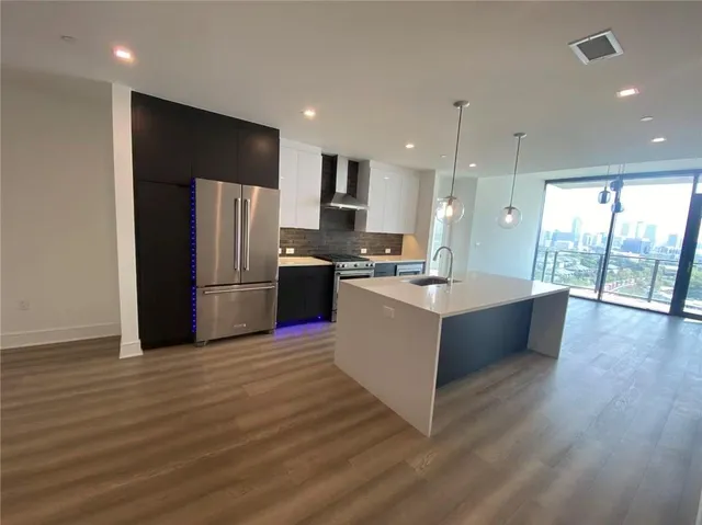 a large kitchen with stainless steel appliances kitchen island a large counter top and a wooden floors