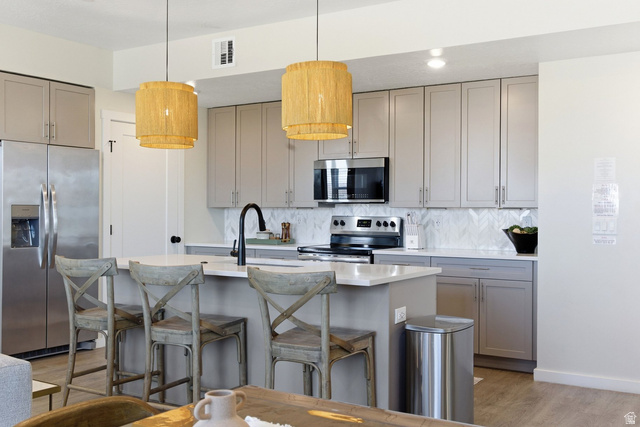 961 West Akoya Pearl Road, Unit 300 St. George, UT 84790 - Photo 14 of 60 Kitchen with gray cabinets, stainless steel appliances, a kitchen bar, a kitchen island with sink, and light wood-type flooring