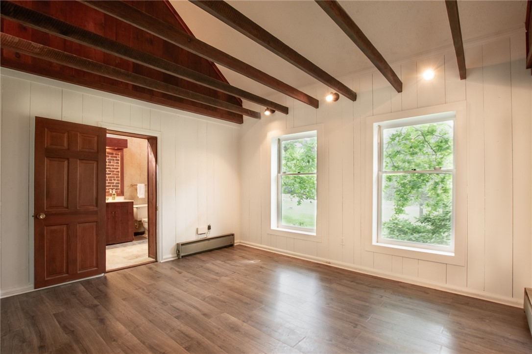 200 Chenault Road Townville, SC 29689 - Photo 18 of 47 Exposed beams complement the rich wood flooring, offering rustic elegance to this versatile area with abundant natural illumination.