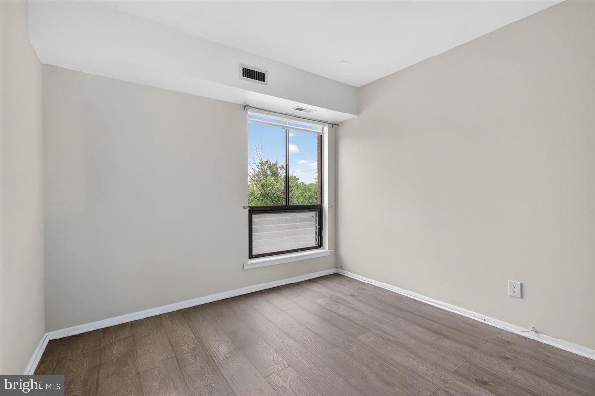 8930 Krewstown Road, Unit 310 Philadelphia, PA 19115 - Photo 22 of 32 an empty room with wooden floor and windows