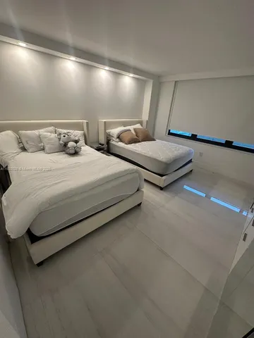 a spacious bedroom with two bed and a night stand