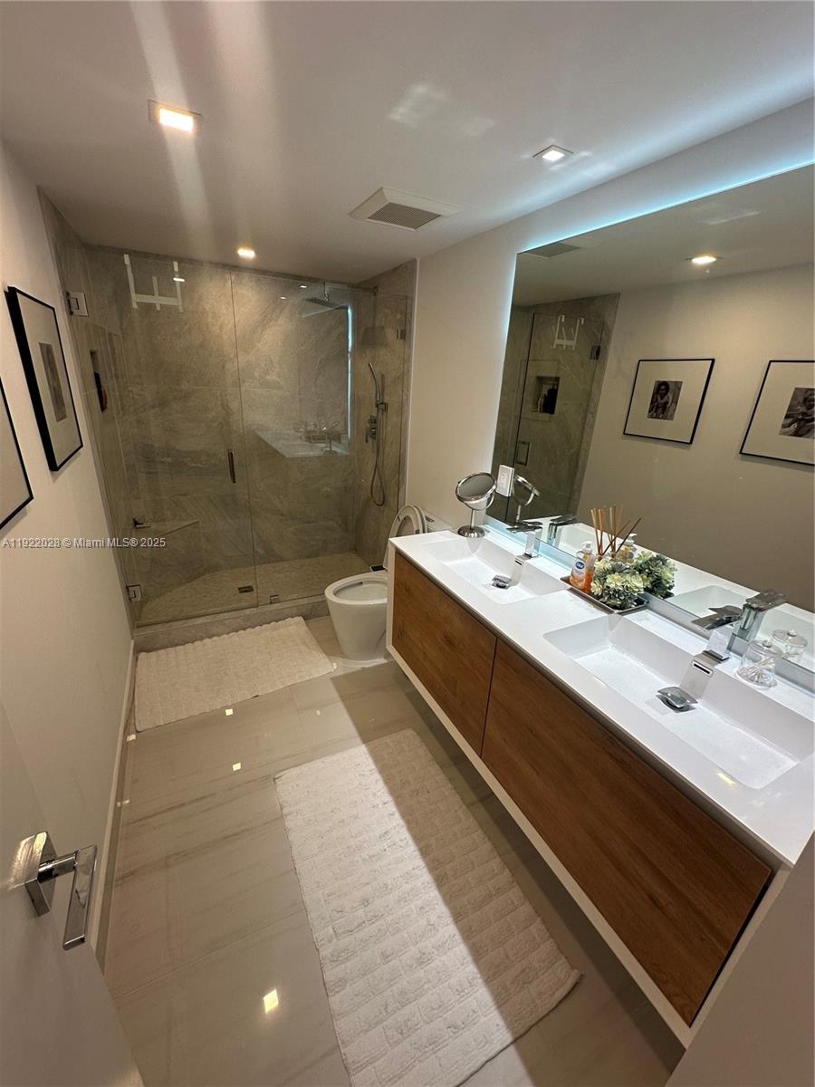 9801 Collins Avenue, Unit 19P Bal Harbour, FL 33154 - Photo 9 of 10 a bathroom with a double vanity sink toilet mirror and shower