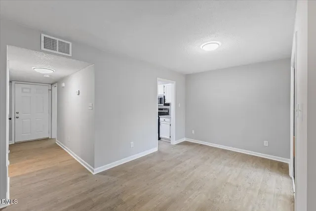 a view of an empty room with wooden floor and closet