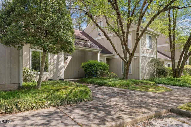 a view of a yard in front of a house with plants and large trees