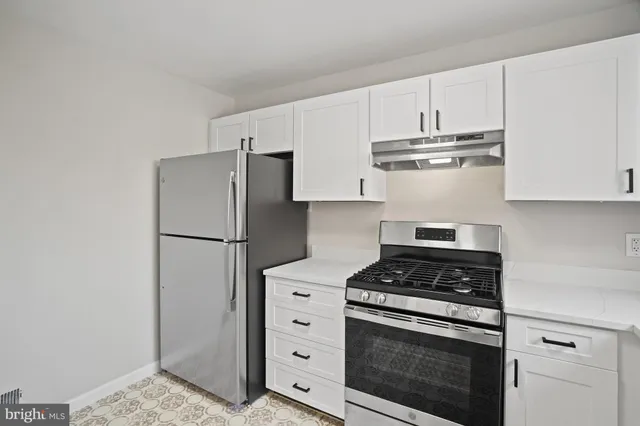 a kitchen with white cabinets and wooden floors