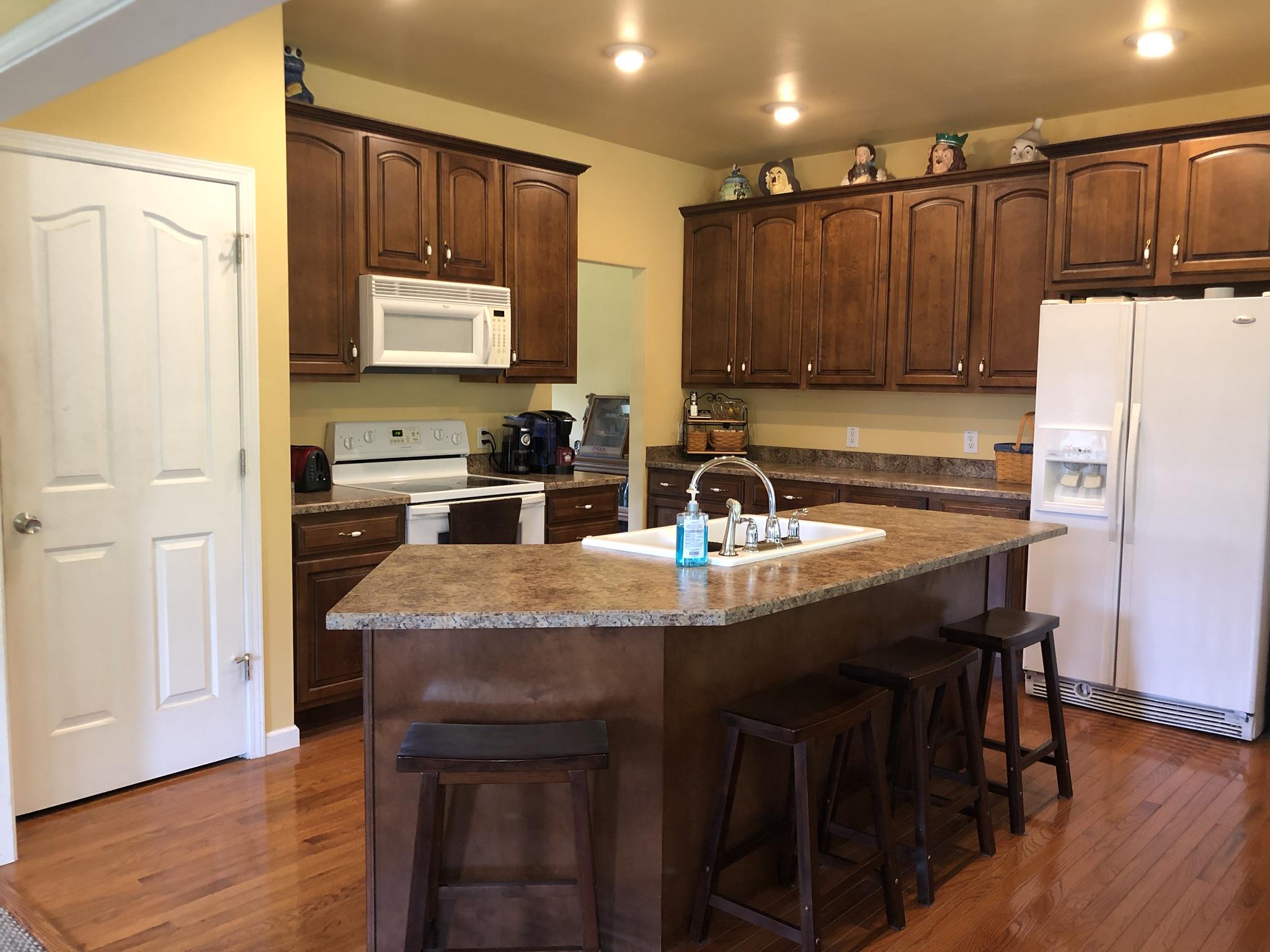 3046 Wayside Road Manchester, TN 37355 - Photo 10 of 30 a kitchen with kitchen island granite countertop a sink a refrigerator and a stove with wooden floor