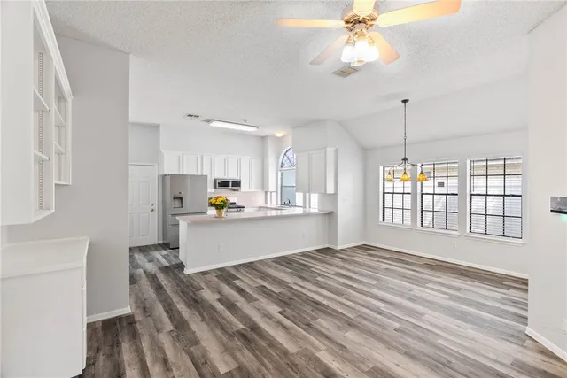 a large white kitchen with kitchen island a stove a sink dishwasher and a refrigerator with wooden floor