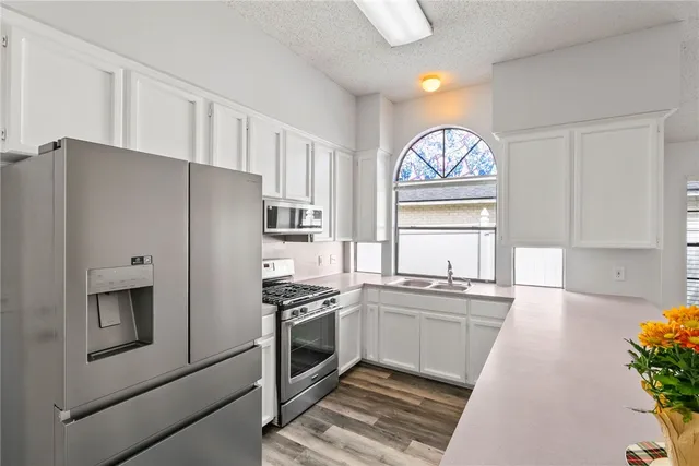 a kitchen with stainless steel appliances a refrigerator a stove a sink and a window