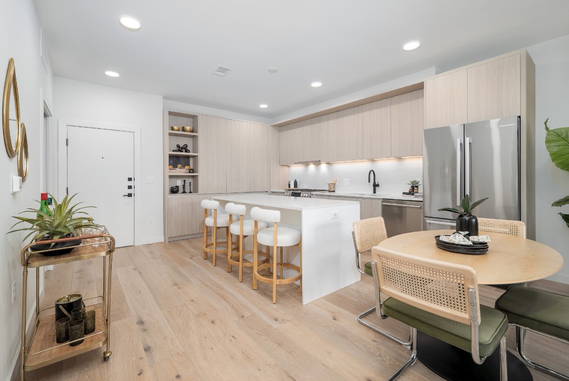 2209 South 1st Street, Unit 334 Austin, TX 78704 - Photo 8 of 28 a kitchen with stainless steel appliances kitchen island granite countertop a table chairs and a refrigerator