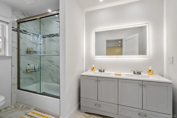 a bathroom with a double vanity sink mirror and shower