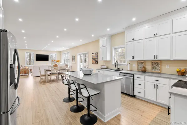 a kitchen with stainless steel appliances granite countertop a table chairs sink refrigerator and cabinets