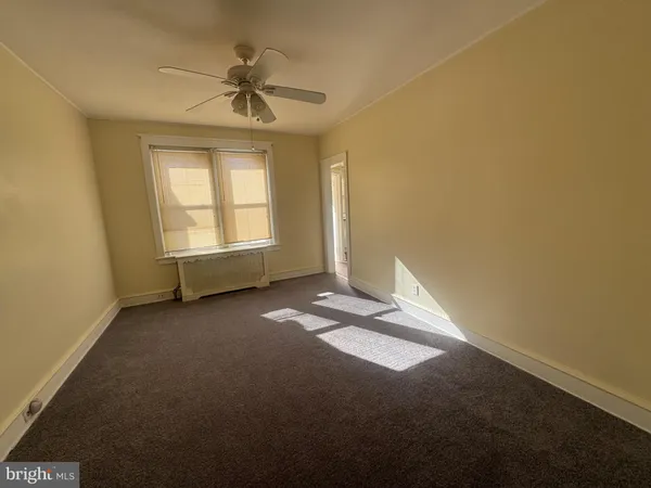 an empty room with a ceiling fan and window
