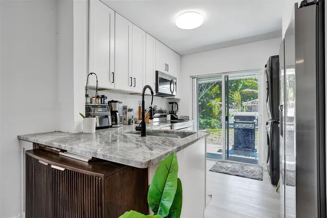 a room with kitchen island granite countertop a sink a counter top space and living room view