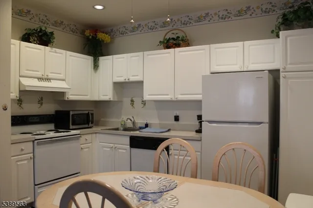 a kitchen with stainless steel appliances granite countertop a refrigerator sink stove and white cabinets
