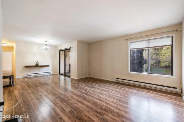 a view of an empty room with a window and wooden floor