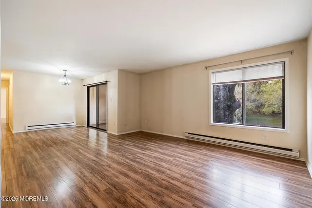 a view of an empty room with window and wooden floor