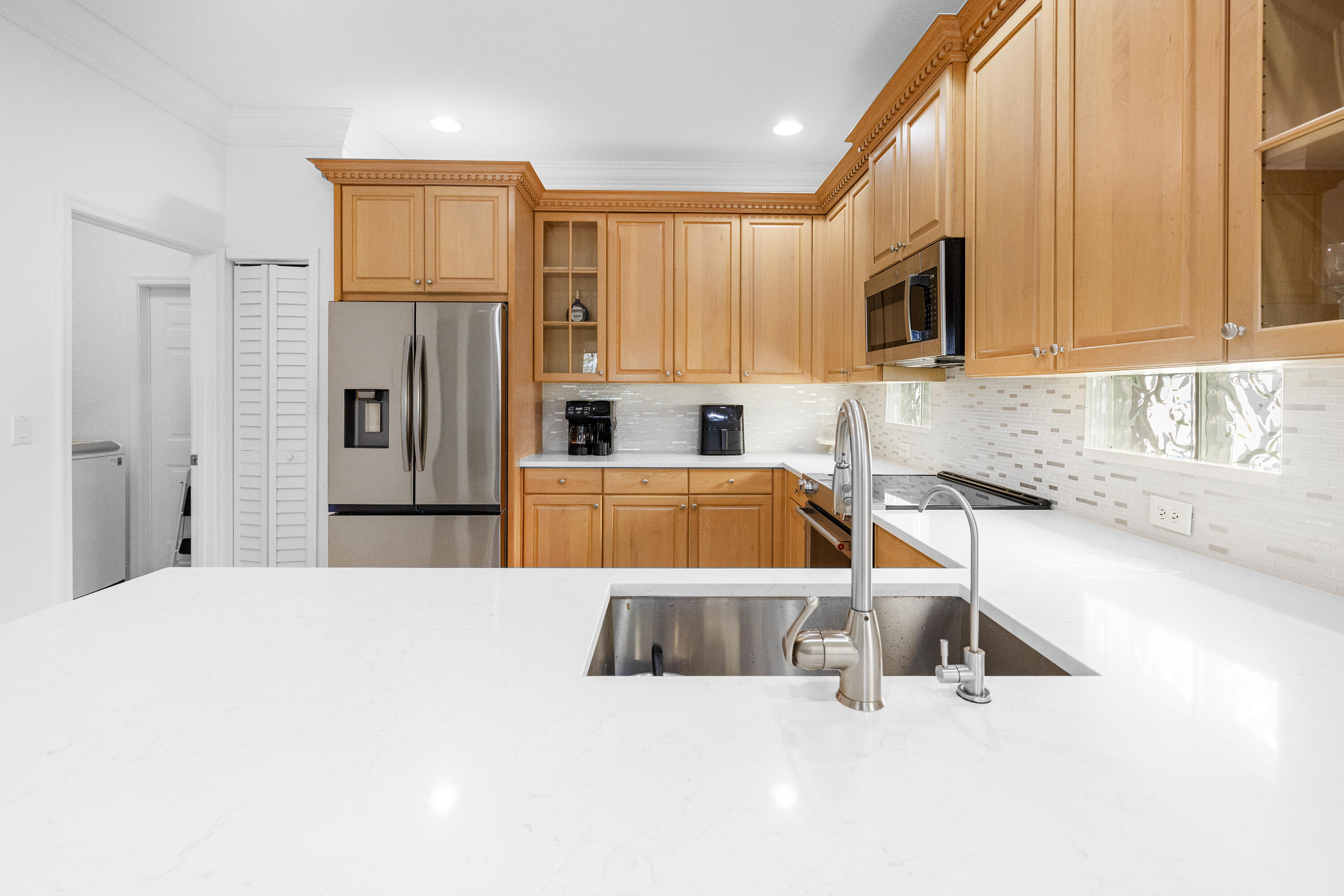 6575 Spring Meadow Drive Greenacres, FL 33413 - Photo 15 of 51 a kitchen with stainless steel appliances kitchen island sink refrigerator and microwave