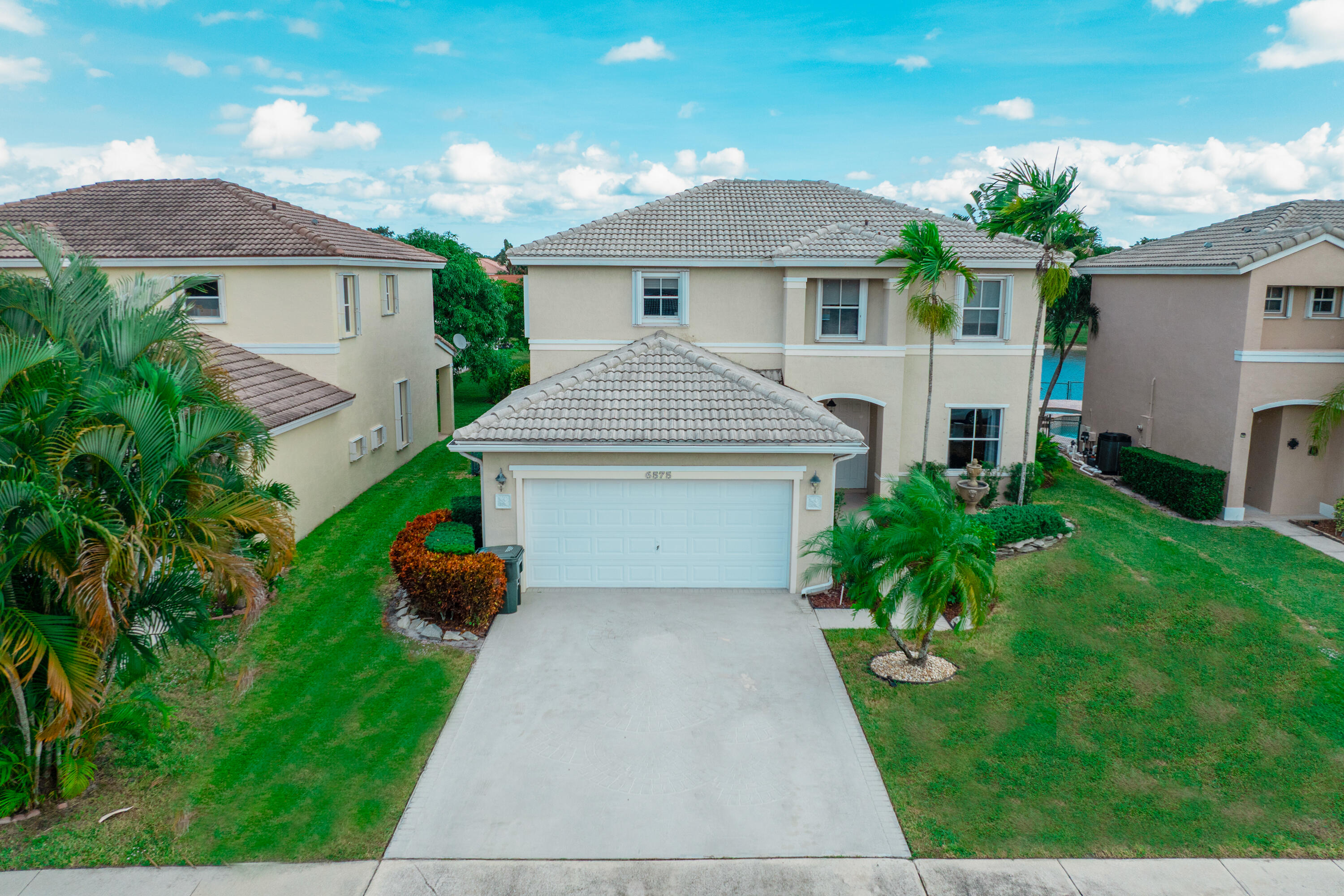 6575 Spring Meadow Drive Greenacres, FL 33413 - Photo 46 of 51 a front view of a house with a yard and garage