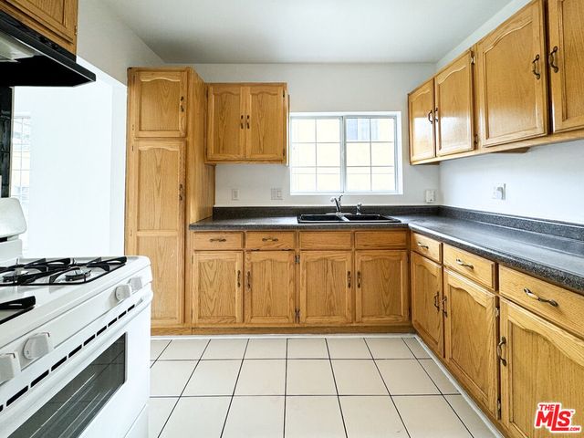 a kitchen with granite countertop a stove a sink and a refrigerator